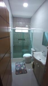 La salle de bains est pourvue de toilettes et d'une douche en verre. dans l'établissement Casa aconchegante com piscina e bem localizada, à Foz do Iguaçu