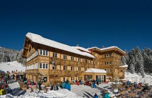 a large wooden building with a snow covered roof at Auenhütte in Hirschegg