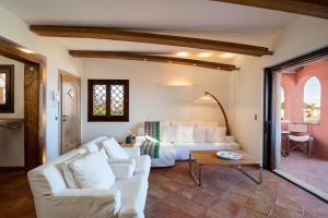 een woonkamer met een witte bank en een bed bij Le case del golfo in Golfo Aranci