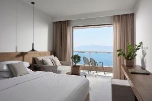 a hotel room with a bed and a view of the ocean at Michelangelo Resort & Spa in Agios Fokas