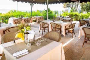a restaurant with white tables and chairs and tables with flowers at Hotel Du Parc in Garda