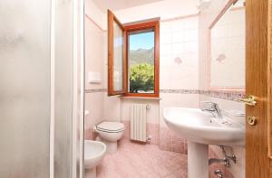 ein Bad mit einem Waschbecken, einem WC und einem Fenster in der Unterkunft Residence Casa Gardola, GTSGroup in Tignale