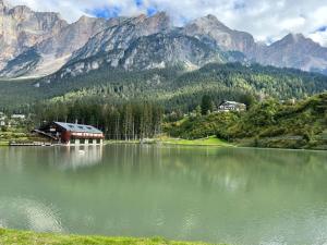 un lago con una casa y montañas en el fondo en Mansarda su due livelli nel cuore delle Dolomiti, en San Vito di Cadore