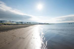 a sandy beach with footprints in the water at 2-bedroom Holiday Home With Great Outdoor Space in Kidwelly