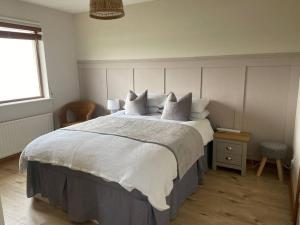 a bedroom with a large bed with white sheets and pillows at Whitepark Cottage - your home away from home in Ballycastle