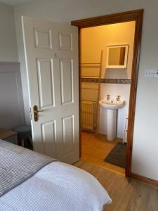a bedroom with a bed and a bathroom with a sink at Whitepark Cottage - your home away from home in Ballycastle