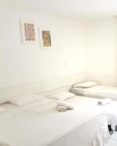three beds in a room with white walls at Pousada Mar de Maceió in Maceió