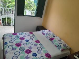 1 dormitorio con 1 cama con sábanas de flores y ventana en CASA FLOR DE LIZ en Villavieja