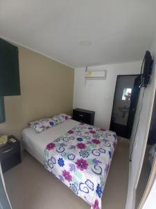 Dormitorio pequeño con cama con edredón de flores en CASA FLOR DE LIZ, en Villavieja