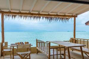 eine Terrasse mit einem Tisch, Stühlen und Meerblick in der Unterkunft Riviera Beach Hotel in Bophut 