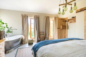 a bedroom with a tub and a bed and a bath tub at Fledgling Barn: stunning new coastal holiday home in Kingsbridge