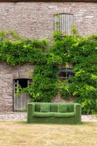 a green couch sitting in front of a brick building at Fledgling Barn: stunning new coastal holiday home in Kingsbridge