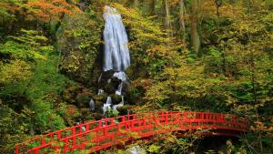 a red bridge in front of a waterfall and a red bridge at ANA Crowne Plaza Resort Appi Kogen, an IHG Hotel in Hachimantai