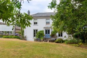 an exterior view of a white house with a yard at Fledgling Barn: stunning new coastal holiday home in Kingsbridge