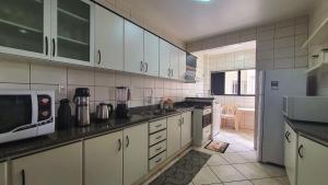 a kitchen with white cabinets and a white refrigerator at Mirante das Aguas de Piratuba in Piratuba