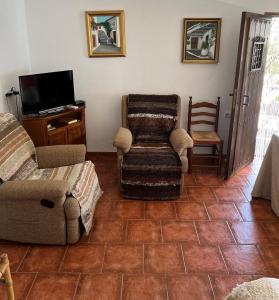 - un salon avec un canapé, une chaise et une télévision dans l'établissement Huerta La Niña Arenas, à Órgiva