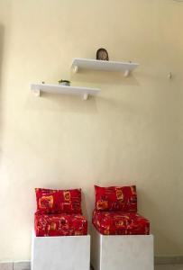 a room with two red pillows and shelves on the wall at Casa acolhedora em Bananeiras-PB in Bananeiras