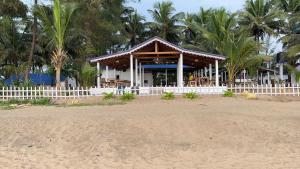 um pavilhão numa praia com palmeiras ao fundo em Vibes and Tides Beach Resort by Enlightened Vagabond em Gokarna