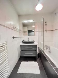 uma casa de banho branca com um lavatório e uma banheira em Lagrive - avec VUE panoramique em Reims