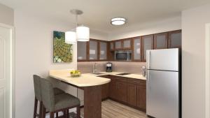 a kitchen with a white refrigerator and wooden cabinets at Staybridge Suites - Cedar Park - Austin N, an IHG Hotel in Cedar Park