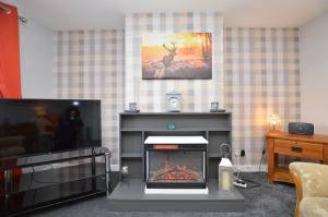 a living room with a fireplace and a tv at Anchor View in Ardrishaig