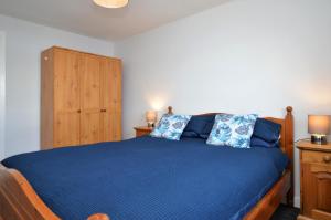 a bedroom with a blue bed and a wooden cabinet at Anchor View in Ardrishaig