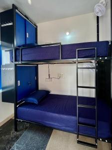 a bunk bed in a room with purple bunk beds at Vibes and Tides Beach Resort by Enlightened Vagabond in Gokarna