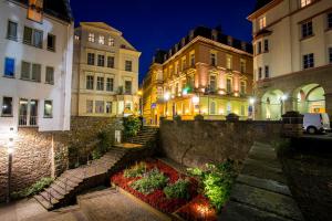 uma rua da cidade à noite com edifícios e flores em Aparthotel am Münzplatz em Koblenz