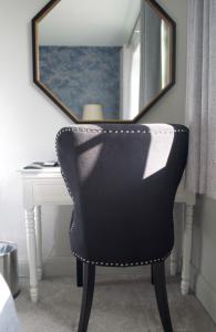 uma cadeira preta sentada em frente a uma secretária com um espelho em The Binsted Inn em Alton