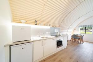 cocina con armarios blancos y techo de madera en Cultybraggan Hut 36, en Mill of Fortune