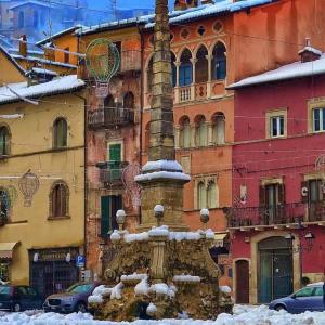 una fontana coperta di neve di fronte a un edificio di Mini House Tagliacozzo a Tagliacozzo