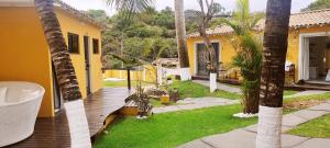 un patio trasero con una terraza de madera y una casa amarilla en Pousada Gente Bonita La Mansion, en Búzios