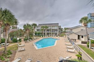 a swimming pool with lounge chairs and a building at Convenient PCB Condo with Pool Access Walk to Beach in Panama City Beach