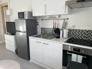 uma cozinha com armários brancos e um frigorífico de aço inoxidável em Studio meublé et lumineux 20m2 em Vittel
