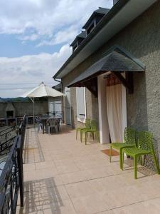 a patio with green chairs and tables and umbrellas at La POSADA in Ibos