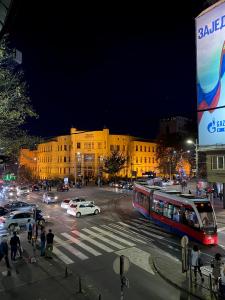 eine belebte Stadtstraße mit Bus und Auto nachts in der Unterkunft Grand Royal in Belgrad