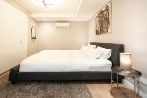 a bedroom with a large white bed and a table at Greenpoint Designer Apartment near Stadium & Waterfront in Cape Town