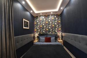 1 dormitorio con 1 cama y papel pintado con motivos florales en Green Penthouse, en Grudziądz