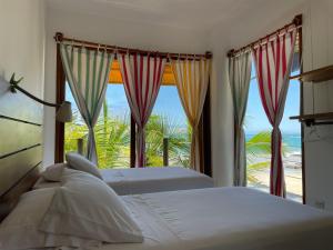 two beds in a bedroom with a view of the ocean at Mi Playa Beach Front Isabela in Puerto Villamil