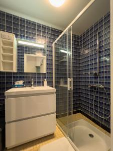 a blue tiled bathroom with a sink and a shower at Le Chardon Bleu, jardin, centre-ville, Saint-Côme-d'Olt in Saint-Côme-dʼOlt