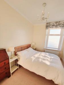 a bedroom with a bed and a dresser and a window at Stunning Aberystwyth South Beach Apartment in Aberystwyth