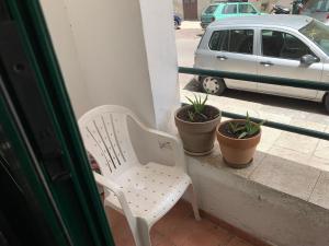 białe krzesło siedzące na balkonie z doniczkami w obiekcie BnB Convalis w mieście Palermo