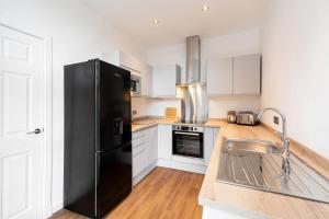 a kitchen with a black refrigerator and a sink at Bissets Bond in Dundee