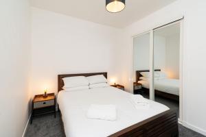 ein Schlafzimmer mit einem großen weißen Bett und einem Spiegel in der Unterkunft Bissets Bond in Dundee