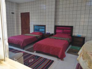 two beds with red covers in a room at Greek Villa in Jerash