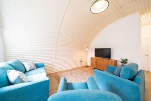 ein Wohnzimmer mit zwei blauen Sofas und einem TV in der Unterkunft Cultybraggan Hut 34 in Mill of Fortune