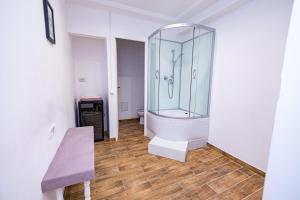 a bathroom with a glass shower and a wooden floor at Pensiunea Ewo in Iaşi