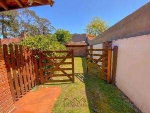 una valla con una puerta de madera en un patio en Casa Tinta Roja 2 de 1 dormitorio en Villa Gesell