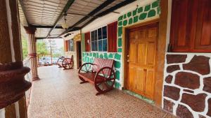 a porch with two benches and a wooden door at Hotel y Restaurante Las Margaritas in Perquín