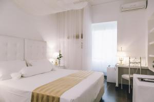 una camera bianca con un grande letto e una scrivania di Eveline 2 - Piscina Privata o Jacuzzi a Sanremo